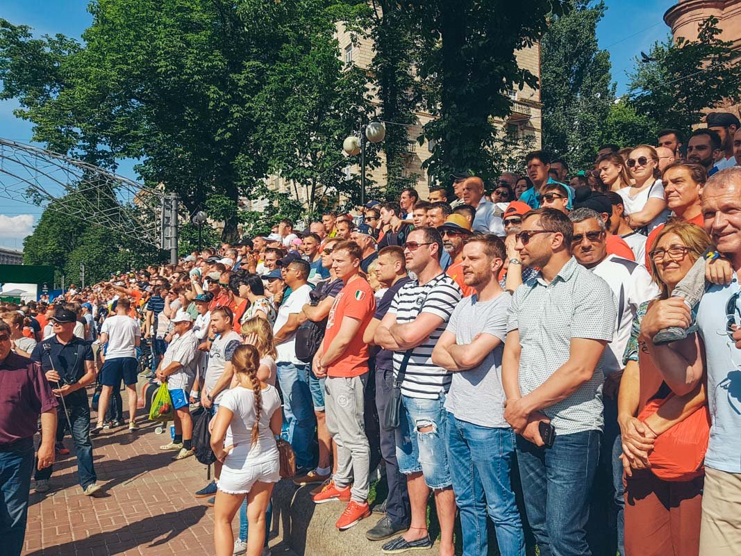 Зрители стоят на клумбах