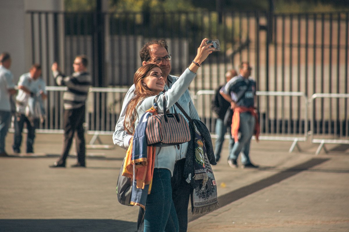Туристы фотографируются на фоне стадиона