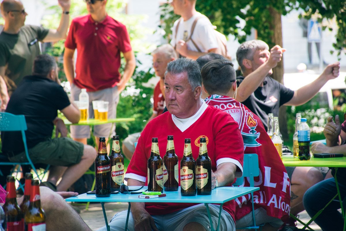 Много фанатов пьют пиво в парке перед матчем