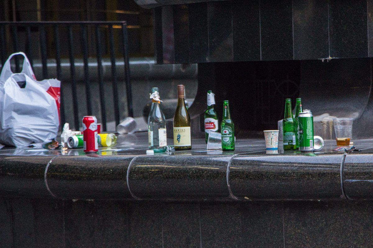 На скамейках и парапетах стоят батареи бутылок