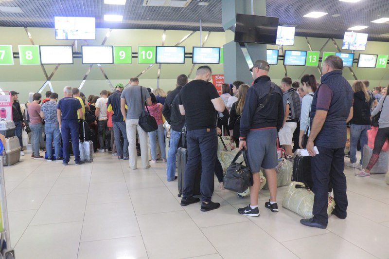 Люди толпятся в зале ожидания и у стоек регистрации