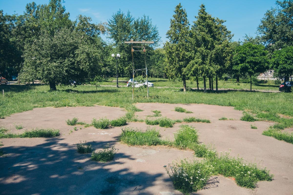 Старая спортивная площадка, где через асфальт проросла трава, а от баскетбольного кольца осталась только аварийная опора Старая спортивная площадка, где через асфальт проросла трава, а от баскетбольного кольца осталась только аварийная опора