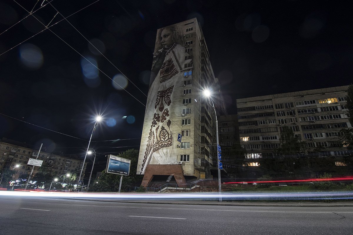 С огромного мурала девушка словно охраняет спокойствие ночного бульвара