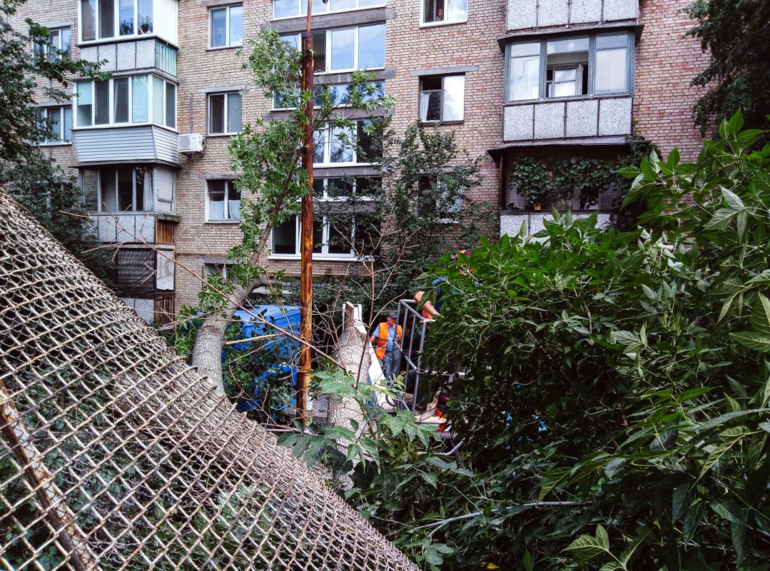 При падении оно завалило металлическое ограждение, проломило бетонный забор и придавило автомобиль