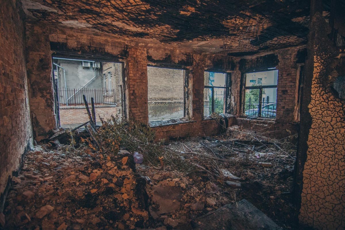 В середине горы мусора обвалившиеся и обгоревшие стены, старые предметы В середине горы мусора обвалившиеся и обгоревшие стены, старые предметы