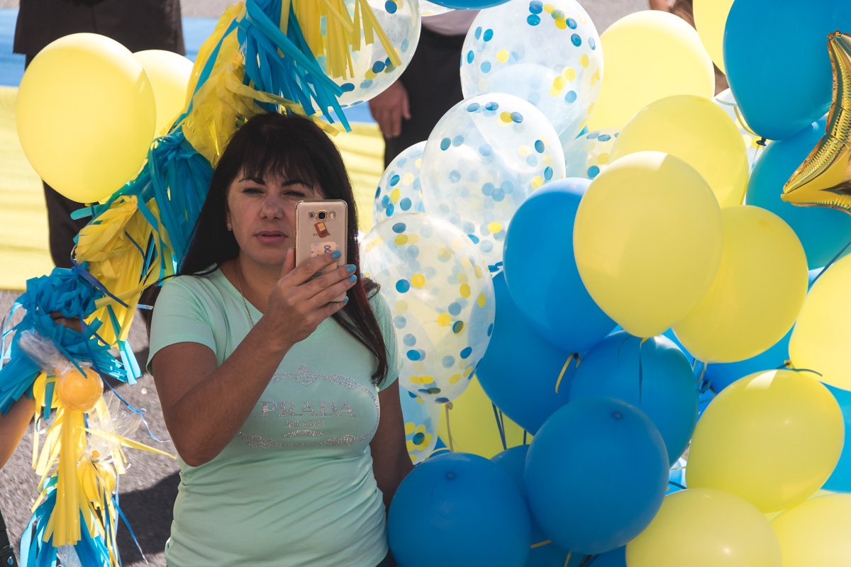 С шариками с символической расцветки, венками, в вышиванках и с улыбками на лице люди праздновали День Флага С шариками с символической расцветки, венками, в вышиванках и с улыбками на лице люди праздновали День Флага