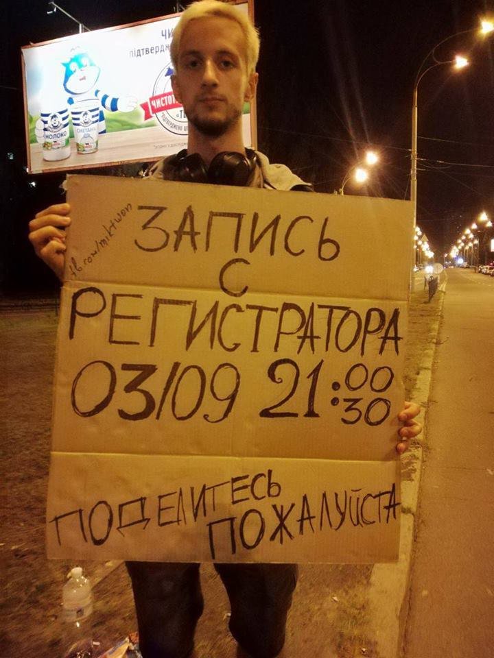 Парень стоит возле места аварии с картонной табличкой и просит о помощи Парень стоит возле места аварии с картонной табличкой и просит о помощи