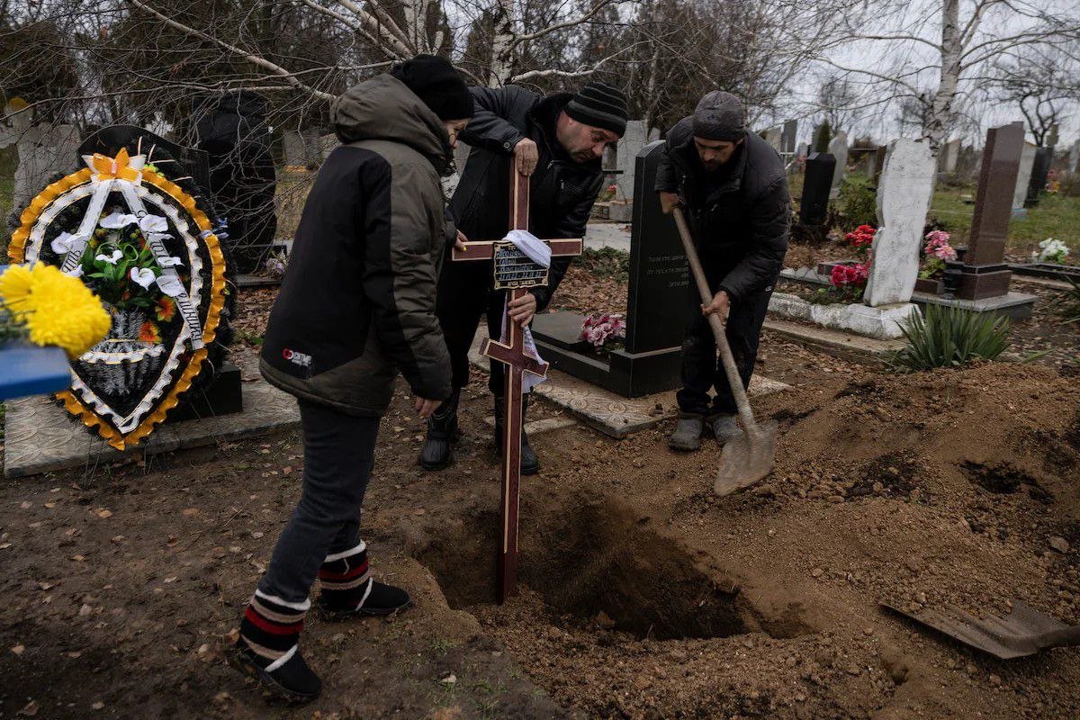 Родина встановлює хрест на могилі Сергійка на кладовищі в Новосолоному Запорізької області України 24 листопада. Фото: Гайді Левін для The Washington Post