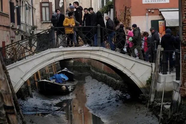 Туристи переходять міст через пересохлий канал під час сильного відливу у Венеції, Італія. Фото: Manuel Silvestri/Reuters