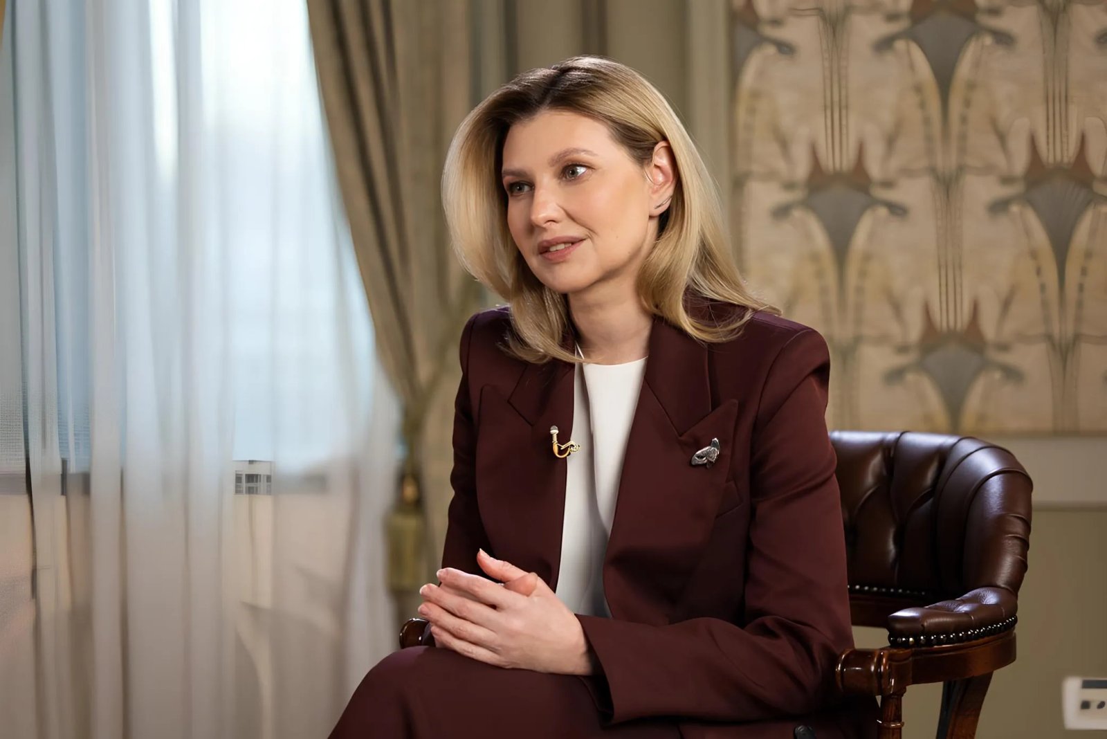 Олена для вигідного контрасту з шоколадним відтінком костюму вдягла молочну блузу та навіть дозволила собі скромні аксесуари - невеличку срібну брошку та продовгуваті сережки, схожі на протяжки. І знову - нічого зайвого!