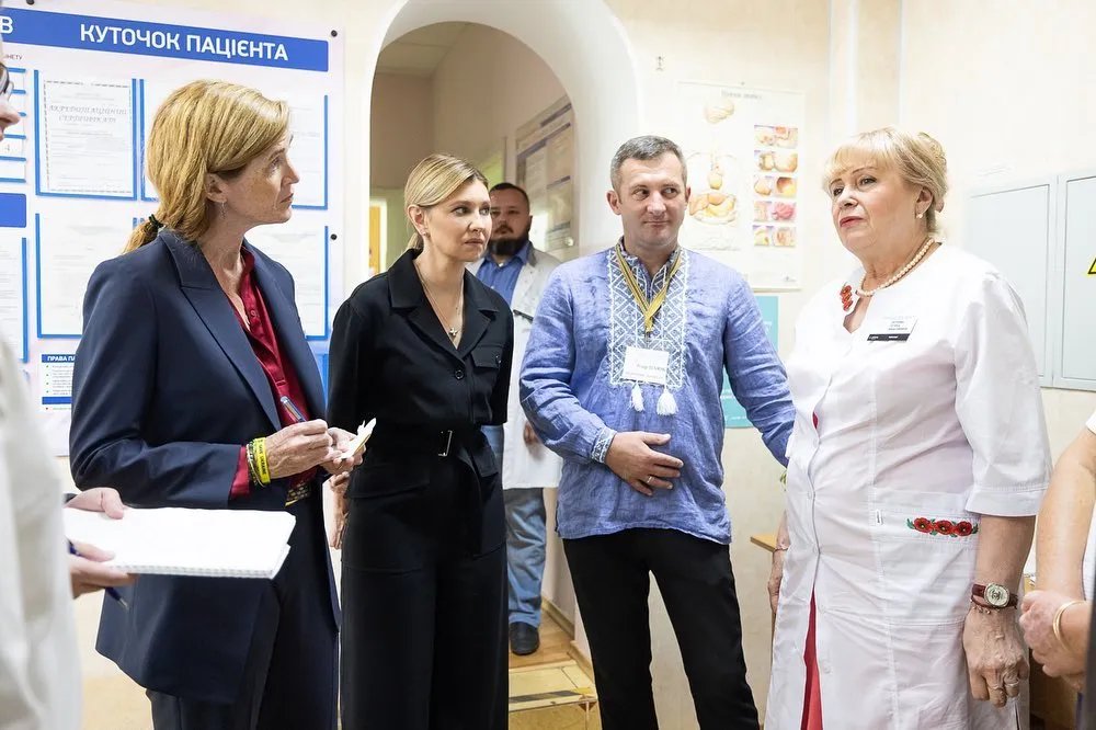 Верхняя часть комбинезона украшена двумя пуговицами, а пояс из той же ткани имеет прямоугольную металлическую пряжку