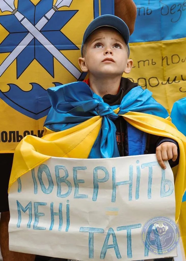 Сын военнопленного держит плакат на западе