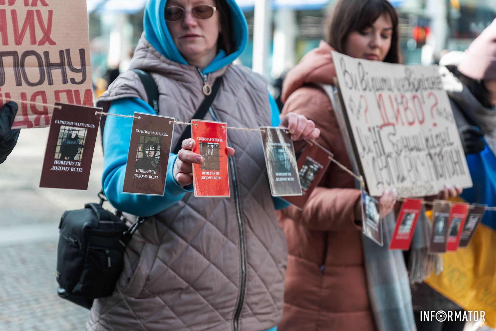 У руках мітингувальники тримають прапори та плакати У руках мітингувальники тримають прапори та плакати