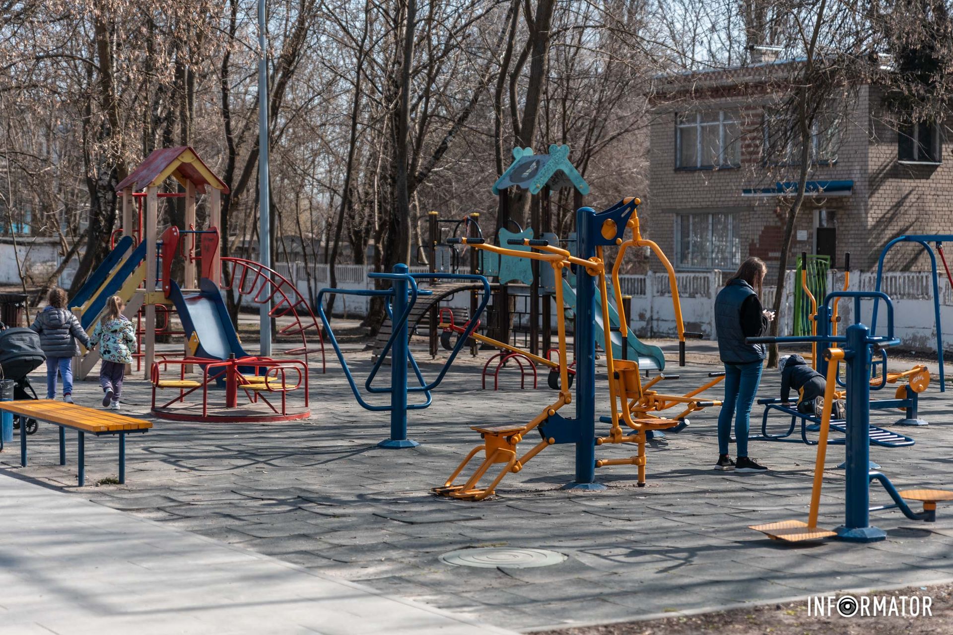 Поруч дитячий майданчик, на якому бавляться діти. 