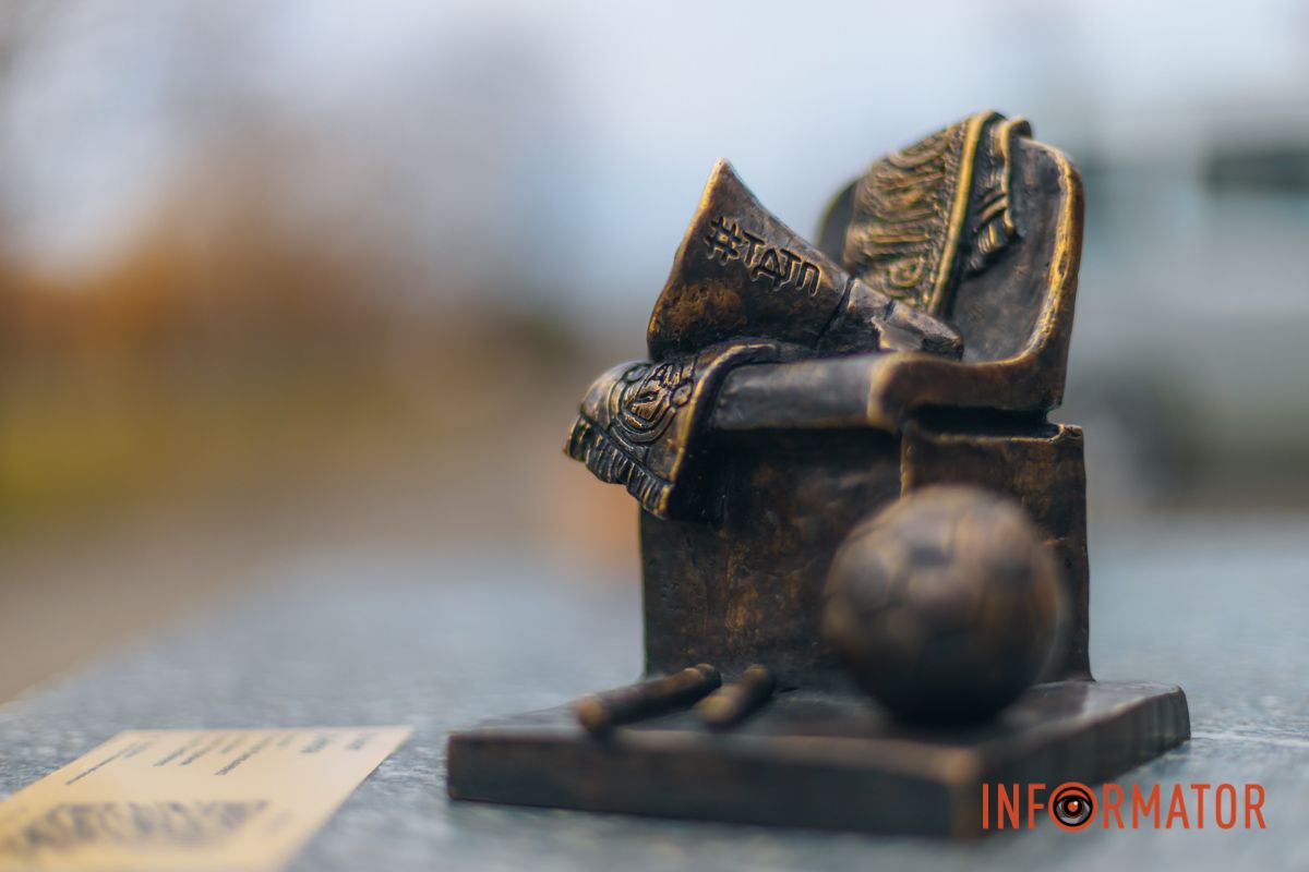 На ній зображені атрибути футбольної символіки - трибуна, рупор, футбольний шарф із написом «Дніпро»