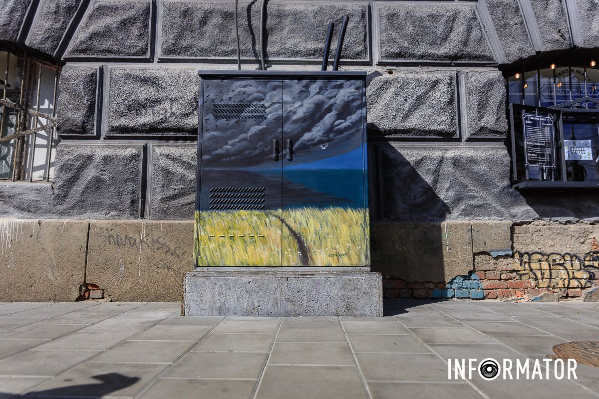 На нем изображено желтое пшеничное поле, черные облака, стая птиц и одна белая птица в небе. Черные облака, птицы и пшеница: в центре Днепра разрисовали электрощиток в стиле стрит-арт 9