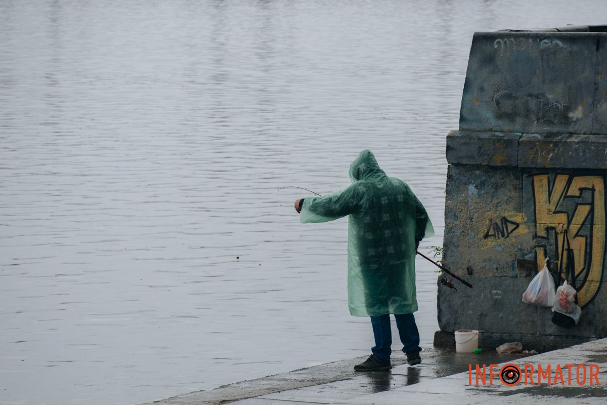 Пешеходы прячутся под зонтиками, рыбаки — у реки.
