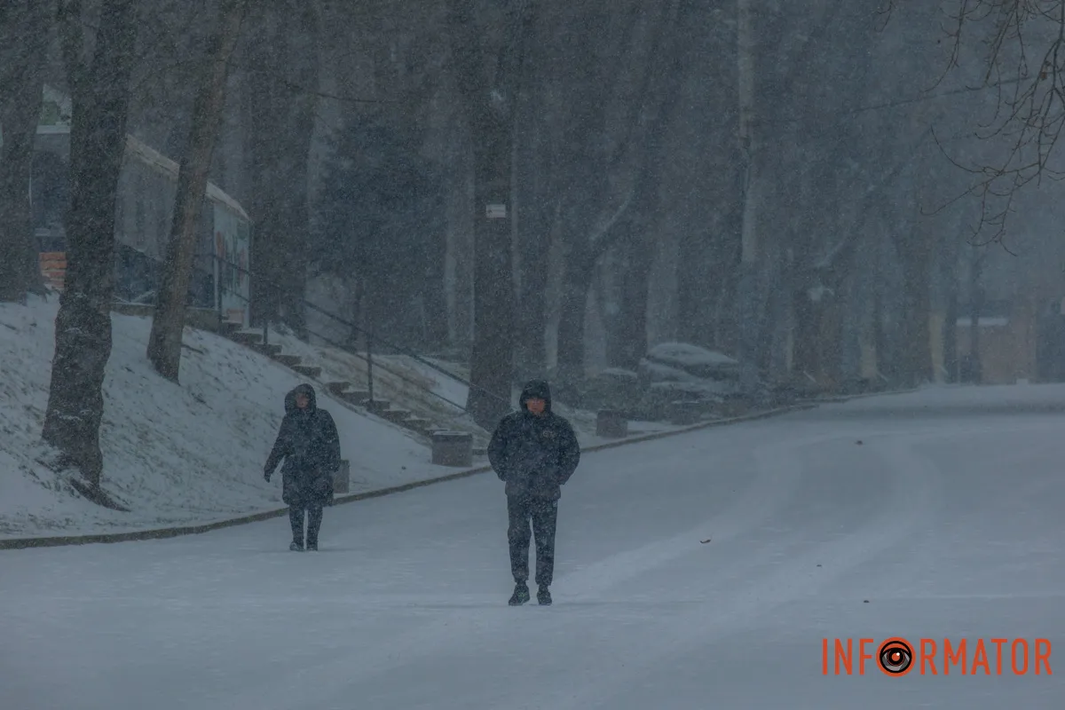 Перехожі ховаються від вітру у капюшонах