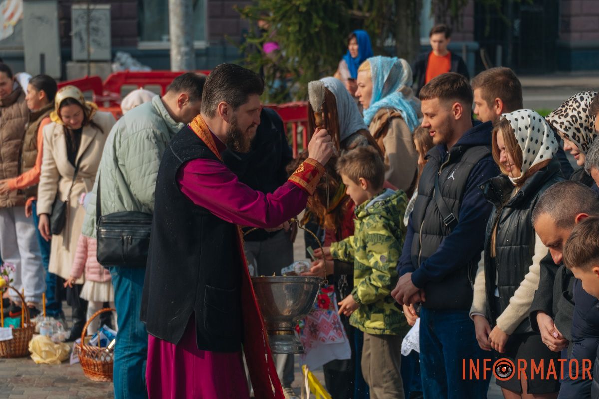 Священник окроплює дніпрян святою водою біля храму