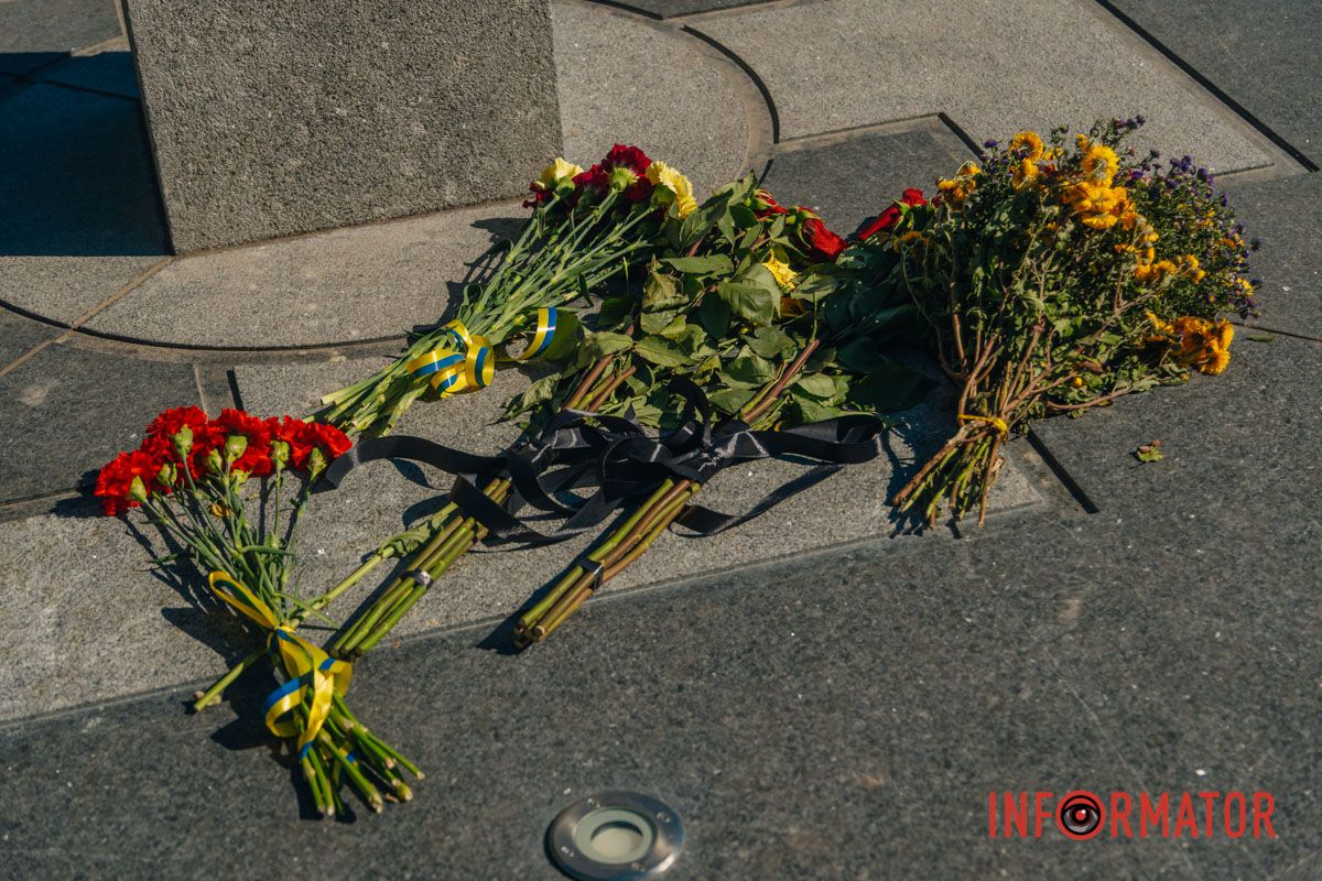 Люди покладають квіти до пам’ятного знака
