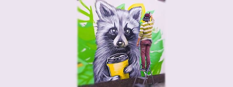 В Киеве на Троещине поселился енот с кофе в лапках: что означает новый мурал