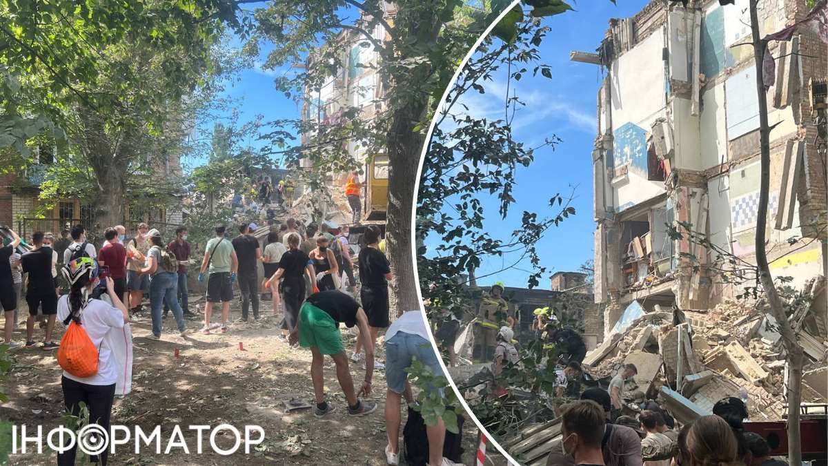 Біля будинку триває розбір завалів, люди вишикувались у шеренгу і передають один одному цеглини та рештки будівлі