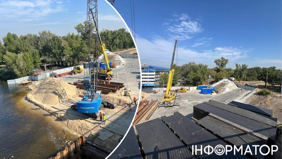 А ось так виглядає будмайданчик зблизька: робітники вже забивають металеві палі просто в дно Дніпра, а біля опор мосту складують великі чорні ящики-пелети