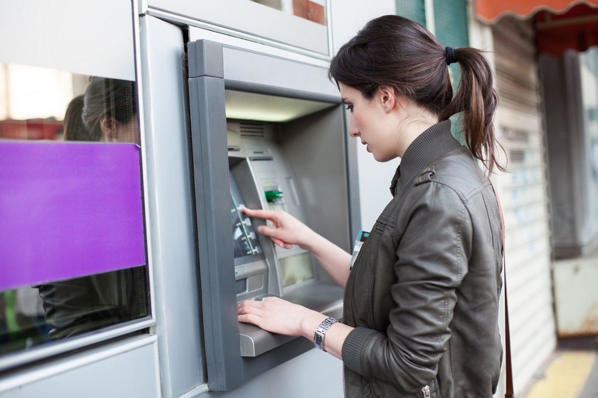 Young Caucasian woman withdrawing money from an ATM.