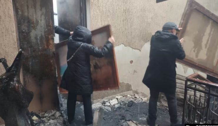 Люди выносят из строения полотна в рамах, некоторые из которых обуглились и сгорели Люди выносят из строения полотна в рамах, некоторые из которых обуглились и сгорели