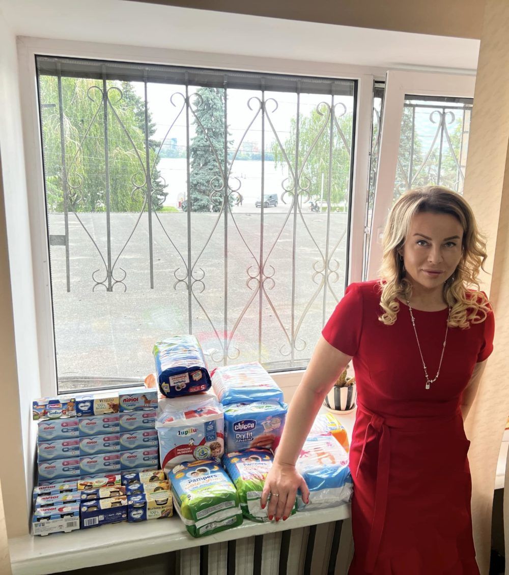 Олена Стєпанян на фоні допомоги, яку розповсюджував Фонд Гуфмана