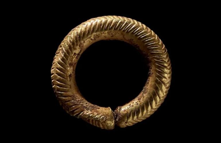 Маленька золота каблучка має складний візерунок у формі шеврона та ялинки.