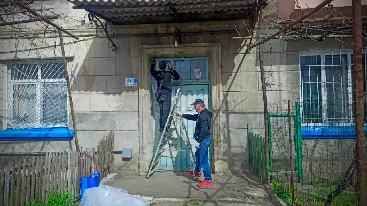 Коммунальные работники чинят окна пленкой Коммунальные работники чинят окна пленкой