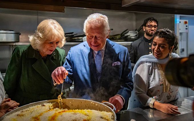 Асма Хан с королем Карлом и королевой Камиллой во время их визита в ее питание в Лондоне. Асма Хан с королем Карлом и королевой Камиллой во время их визита в ее питание в Лондоне.