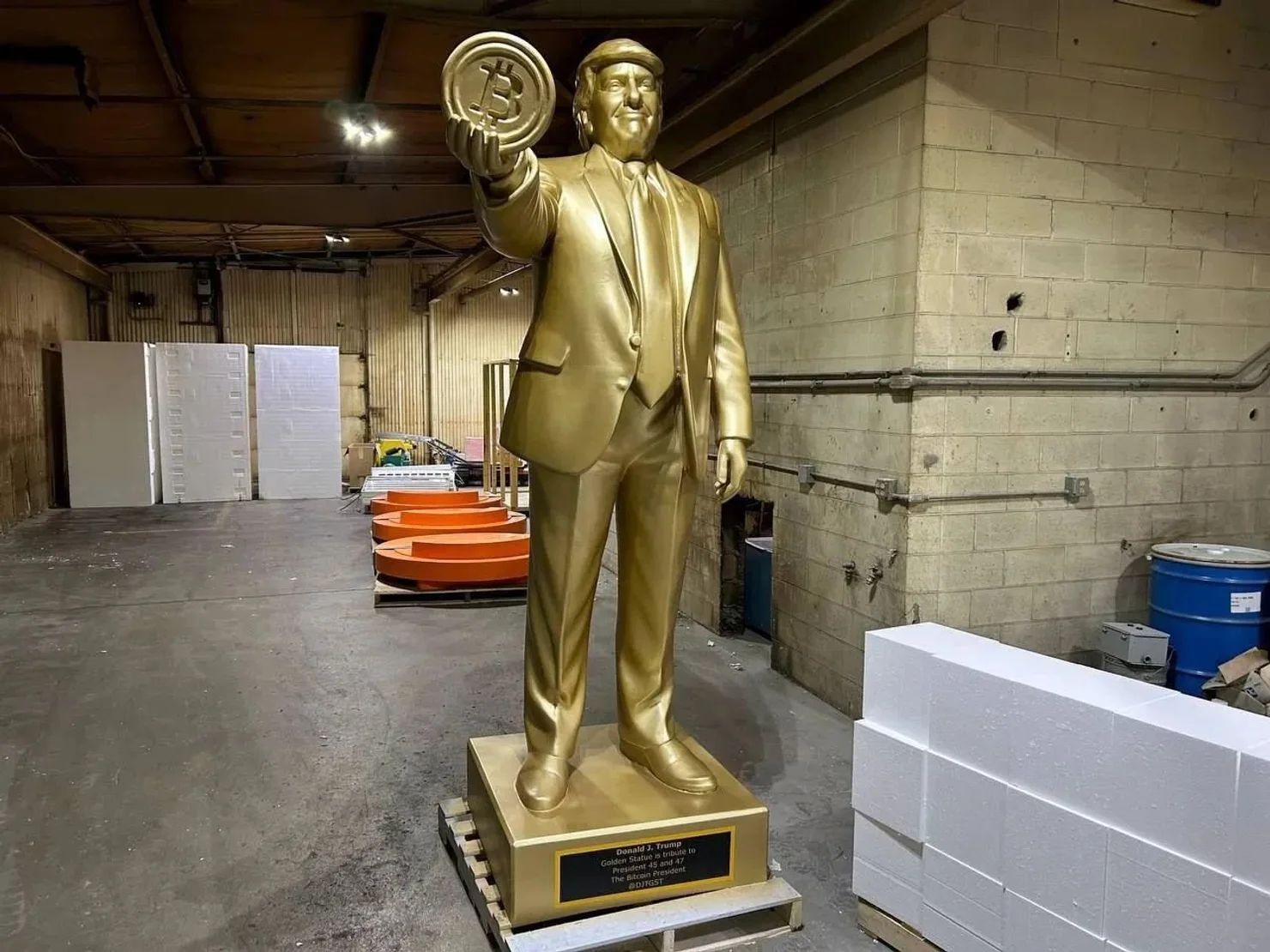 Золотая статуя Трампа с биткойном в руке.