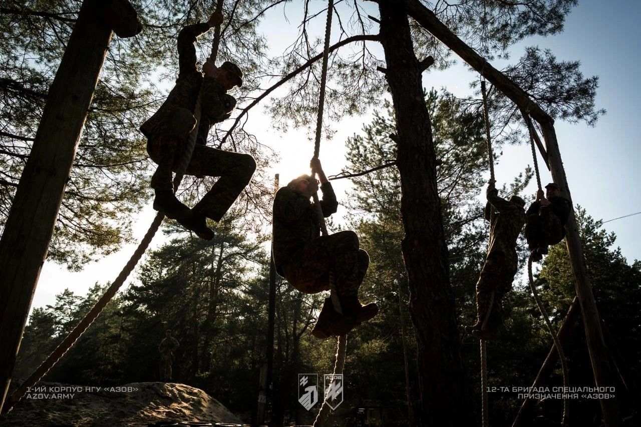 Рекрути 1-го корпусу НГУ «Азов» проходять фізичну підготовку на смузі перешкод під час навчань у лісовій місцевості.