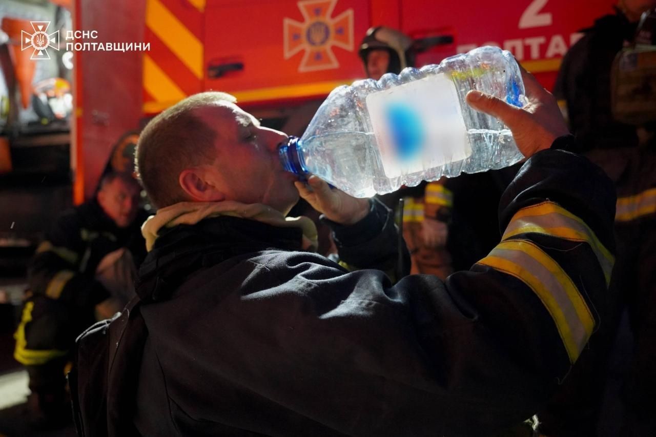 Спасатель пьет воду на месте пожара после атаки Спасатель пьет воду на месте пожара после атаки