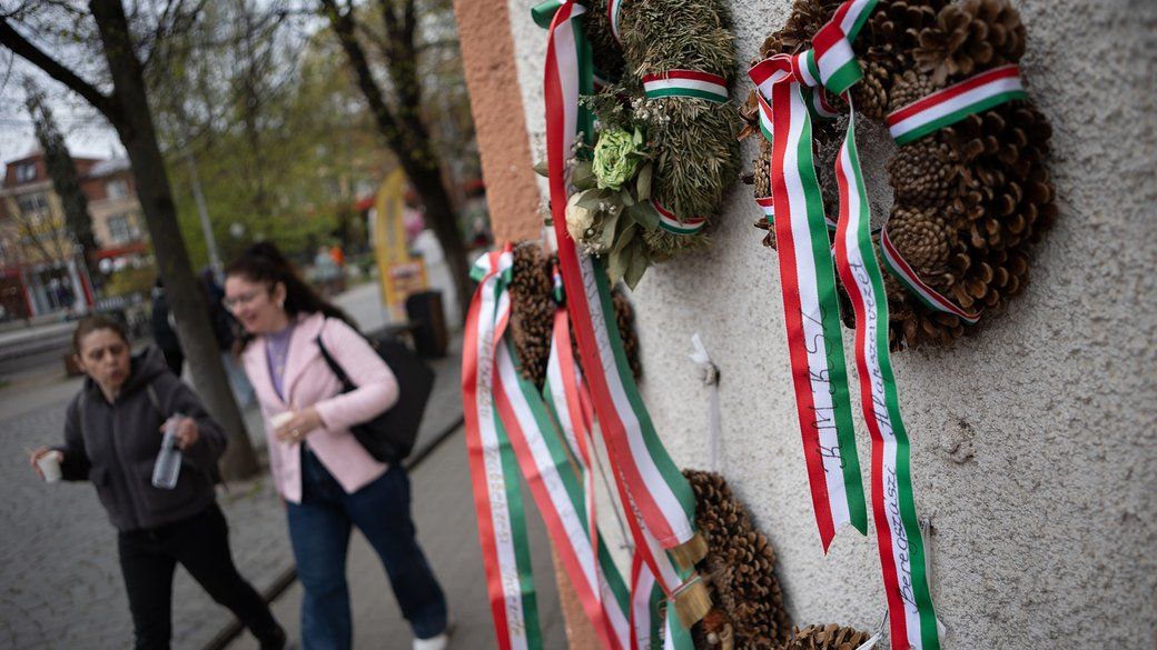 Люди проходят мимо венков с лентами в цветах флага Венгрии на здании Закарпатского областного венгерского драматического театра в Берегово, 2 апреля 2026 года. Такими венками традиционно украшают здание до 15 марта – годовщины Венгерской революции 1848 года. Общественное Новости
