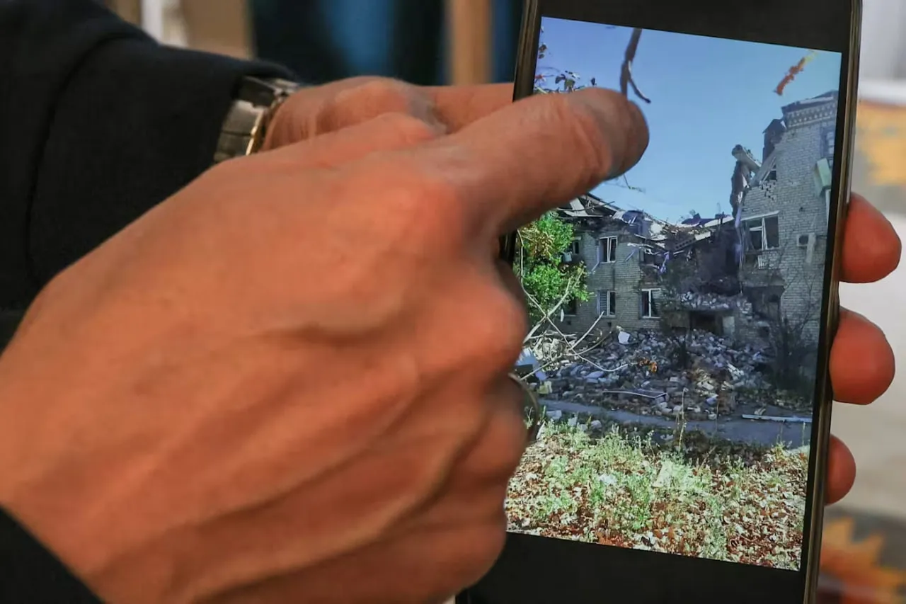 Чоловік, який втік з Олешок, показує фотографію свого зруйнованого сімейного будинку на телефоні. Фото: Reuters