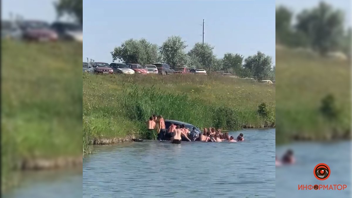 Под Днепром BMW скатился в озеро: на берег машину выталкивали отдыхающие