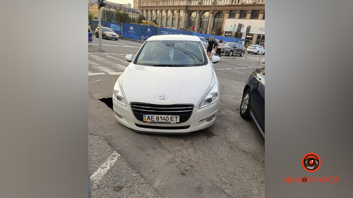 В Днепре возле ЦУМа под Peugeot провалился асфальт: авто из ямы вытаскивали несколько десятков прохожих